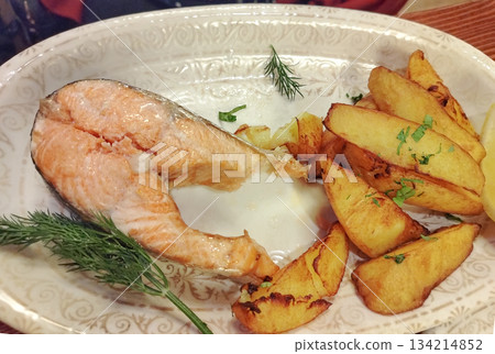 Salmon steak with potato wedges on plate close up horizontal 134214852