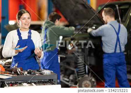 car service worker fills out papers against the background of mechanics car service worker fills out papers against the background of mechanics 134215221