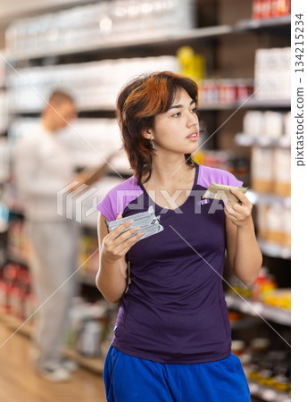 Latin girl chooses sports nutrition protein bar in store 134215234
