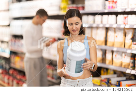 Adult woman buying jar of sports nutrition Adult woman buying jar of sports nutrition 134215562