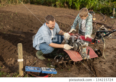 Man and his son are repairing garden equipment 134215724
