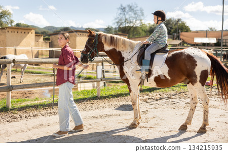 Young woman leading horse with boy riding Young woman leading horse with boy riding 134215935