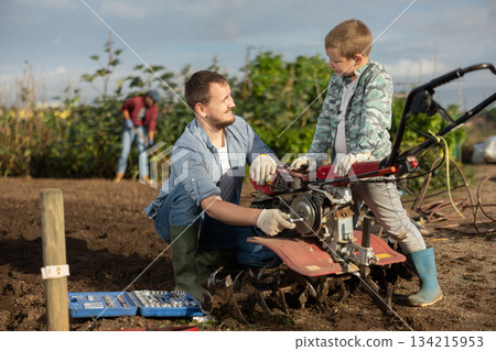 Young man and boy repairing weeding machine 134215953