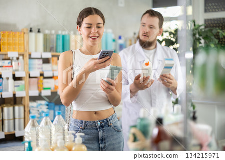 Woman buyer scans cream qr code with man pharmacist 134215971