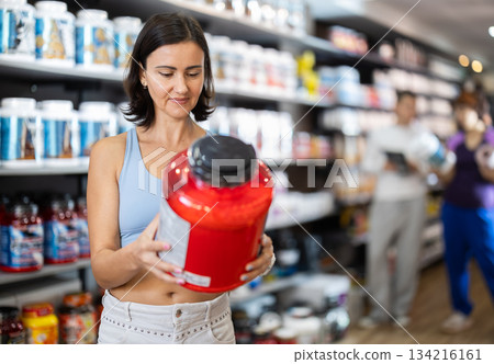Woman chooses protein sports nutrition in store 134216161