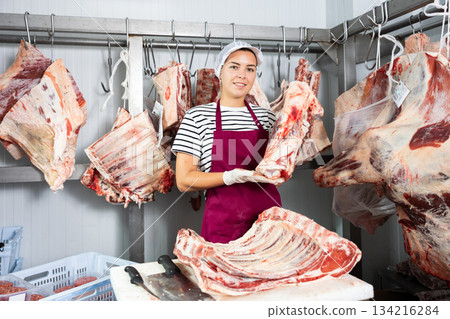 Female butcher is demonstraiting meat to clients indoors 134216284