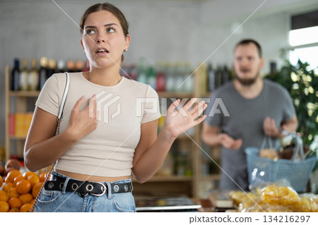 Sullen girl stands with arms crossed on chest, swears with husband and listens to mans accusations 134216297