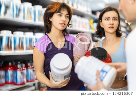 Two women and man choosing jar of sports nutrition Two women and man choosing jar of sports nutrition 134216307