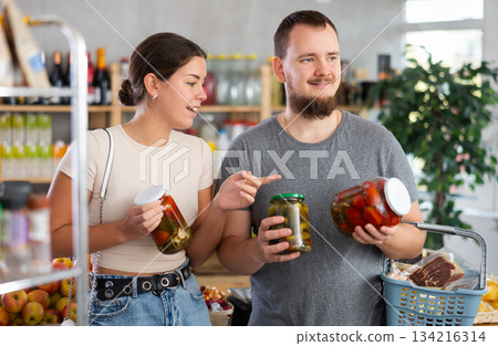 Couple man and woman choosing pickled cucumbers and tomatoes Couple man and woman choosing pickled cucumbers and tomatoes 134216314