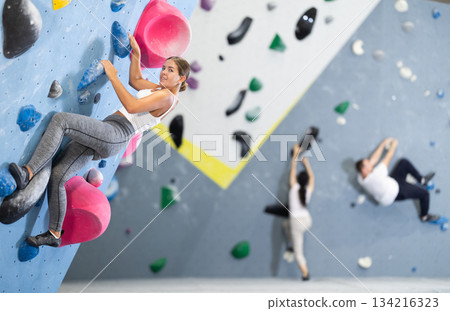 Young woman practicing rock climbing on climbing wall Young woman practicing rock climbing on climbing wall 134216323