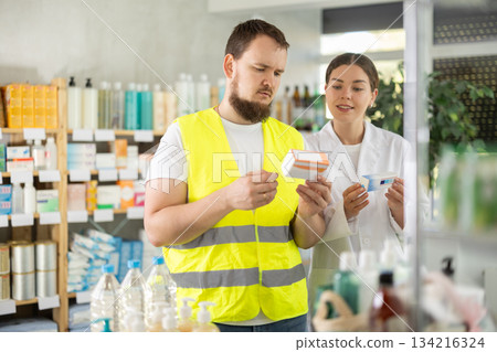 Male builder choosing pills in pharmacy 134216324