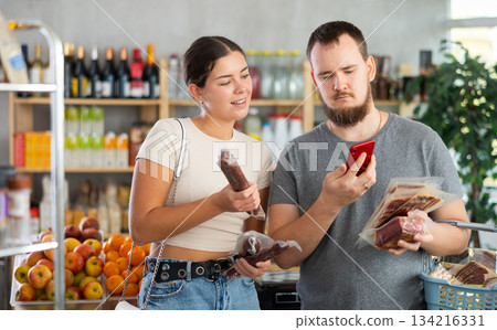 In trading floor, spouses buyers inspects hamon and dried sausage, scan QR code on product label 134216331