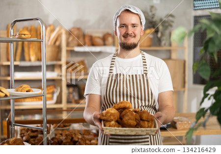 Young male seller with croissants in basket Young male seller with croissants in basket 134216429