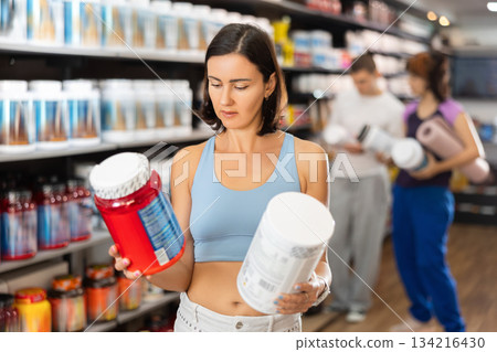 Adult woman buying jar of sports nutrition Adult woman buying jar of sports nutrition 134216430