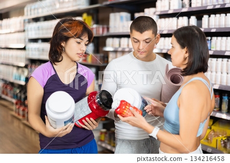 Young guy and women choosing protein powder jar in sports nutrition store 134216458
