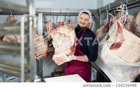 Bearded butcher shop seller preparing beef cuts for sale 134216496