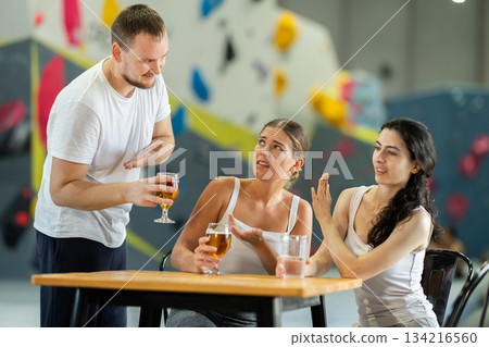 Man tries to pick up young girls after rock climbing training. Girls refuse to talk to him. Man flirting with disappointed girls Man tries to pick up young girls after rock climbing training. Girls refuse to talk to him. Man flirting with disappointed girls 134216560