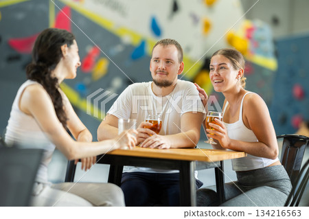 Man and two women talk at table on climbing wall 134216563