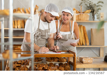 Young girl and guy working in bakery making some records croissants on paper sheets 134216567