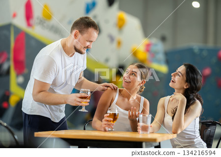 Man approaches to meet two women at climbing wall 134216594