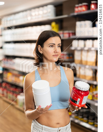 Woman chooses protein sports nutrition in store Woman chooses protein sports nutrition in store 134216635