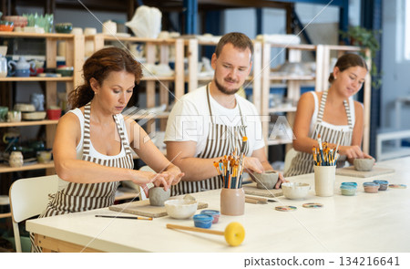Three pottery workshop workers sculpt from raw clay Three pottery workshop workers sculpt from raw clay 134216641