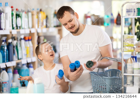 Schoolboy son and dad are choosing trash bags in store Schoolboy son and dad are choosing trash bags in store 134216644