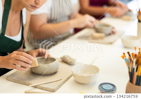 Close up girl forms bowl of clay during master class, top view 134216759