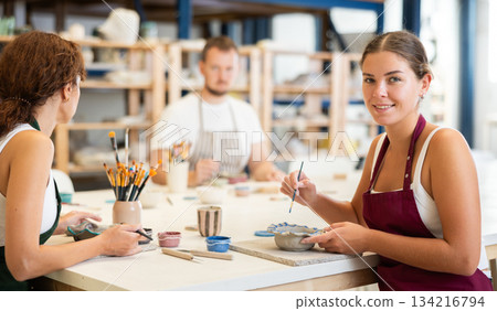 Three craftsperson are busy painting clay products Three craftsperson are busy painting clay products 134216794