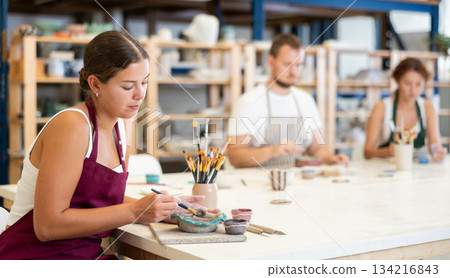 Three craftsperson are busy painting clay products 134216843