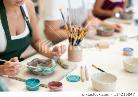 Close up girl paints bowl of clay during master class, top view. 134216847