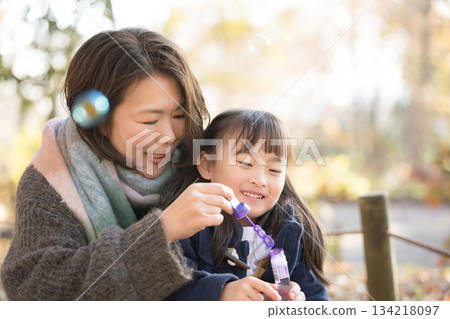 Parents and children playing with soap bubbles in an autumn park. Elderly mother and cute daughter Parents and children playing with soap bubbles in an autumn park. Elderly mother and cute daughter 134218097