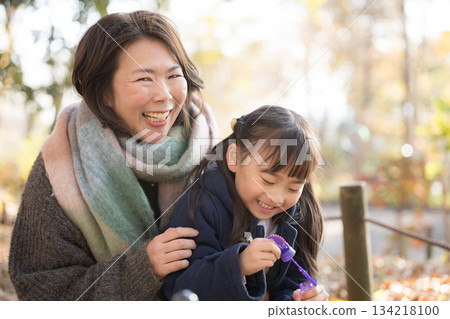 秋日的公園裡,父母和孩子們在玩泡泡。一位年長的母親和她可愛的女兒。 秋日的公園裡,父母和孩子們在玩泡泡。一位年長的母親和她可愛的女兒。 134218100
