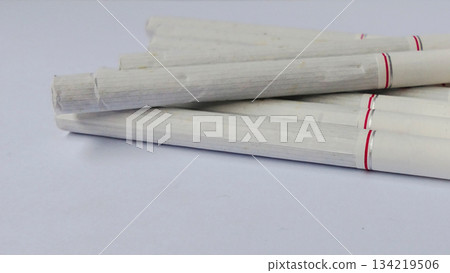 Several white cigarettes were neatly arranged on a clean white surface. Several white cigarettes were neatly arranged on a clean white surface. 134219506