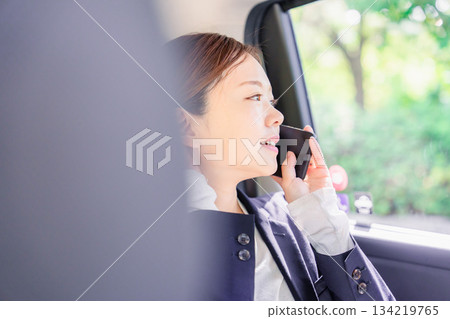 A young saleswoman making a phone call while riding in a taxi A young saleswoman making a phone call while riding in a taxi 134219765