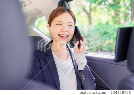 一位年輕的女銷售員在計程車上打電話。 一位年輕的女銷售員在計程車上打電話。 134219768