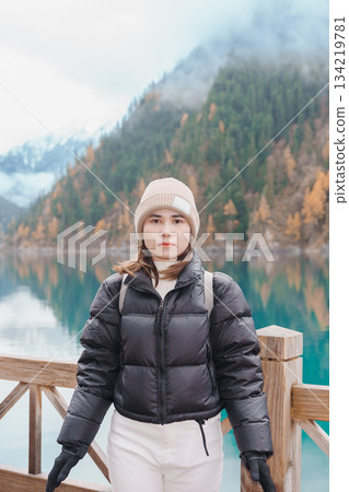 Happy woman traveler travel in jiuzhaigou national park in Sichuan, China. Tourist sightseeing Long lake and snow mountain in Autumn season. Famous Landmark and Vacation near Chengdu, China Happy woman traveler travel in jiuzhaigou national park in Sichuan, China. Tourist sightseeing Long lake and snow mountain in Autumn season. Famous Landmark and Vacation near Chengdu, China 134219781