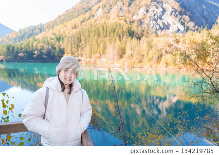 Happy woman traveler travel in jiuzhaigou national park in Sichuan, China. Tourist sightseeing Arrow Bamboo lake and snow mountain in Autumn season. Famous Landmark and Vacation near Chengdu, China Happy woman traveler travel in jiuzhaigou national park in Sichuan, China. Tourist sightseeing Arrow Bamboo lake and snow mountain in Autumn season. Famous Landmark and Vacation near Chengdu, China 134219785