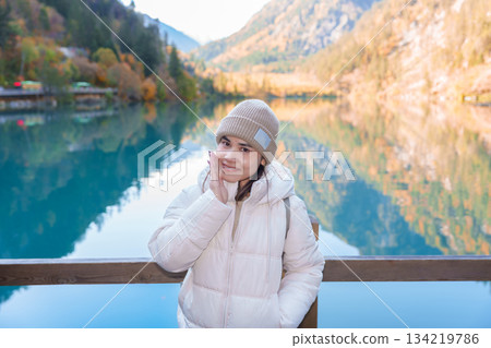 Happy woman traveler travel in jiuzhaigou national park in Sichuan, China. Tourist sightseeing Panda lake and snow mountain in Autumn season. Famous Landmark and Vacation near Chengdu, China 134219786
