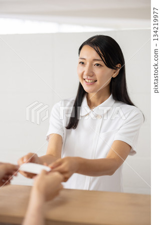A woman in a white coat receiving a card at the reception 134219977