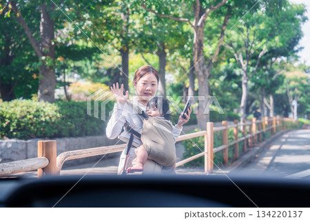 一名背著嬰兒背帶的女子即將被一輛汽車撞到。 一名背著嬰兒背帶的女子即將被一輛汽車撞到。 134220137