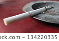 Burning Cigarette Resting on an Ashtray 134220335