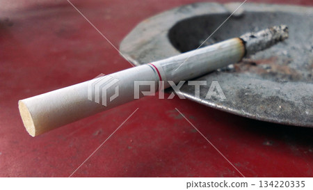 Burning Cigarette Resting on an Ashtray 134220335