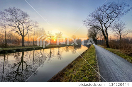 Enjoying the Serene Sunrise Reflections Along a Beautifully Calm Canal Path This Morning Enjoying the Serene Sunrise Reflections Along a Beautifully Calm Canal Path This Morning 134220444