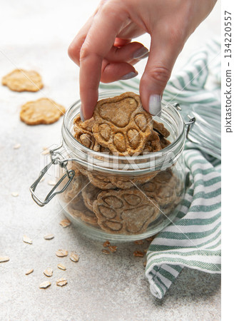 Woman hand taking homemade paw print dog treats from jar Woman hand taking homemade paw print dog treats from jar 134220557