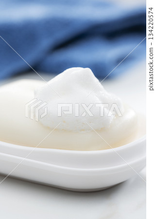 一張乾淨整潔的浴室照片，上面有泡沫豐富的香皂和整齊擺放的毛巾。 134220574