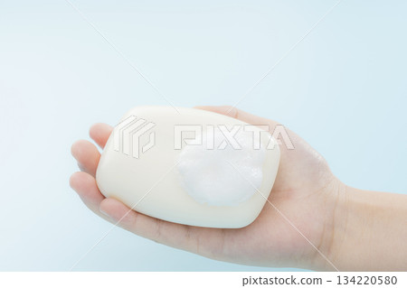 一張乾淨的圖片,畫面中一塊泡沫豐富的肥皂握在孩子的手中。 一張乾淨的圖片,畫面中一塊泡沫豐富的肥皂握在孩子的手中。 134220580