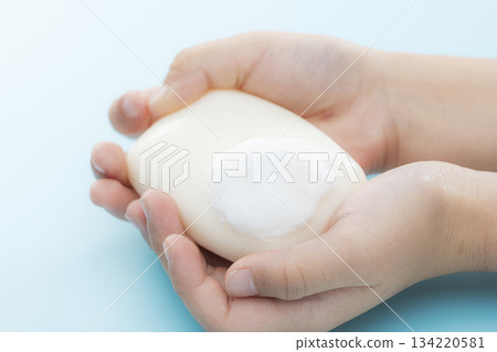 一張乾淨的圖片，畫面中一塊泡沫豐富的肥皂握在孩子的手中。 134220581