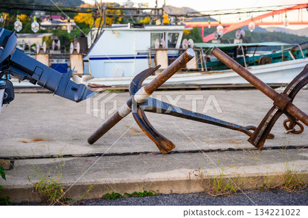 Anchor and outboard motor on the harbor ground 134221022