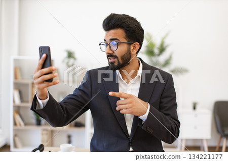 An Indian businessman gestures while on a video call using his smartphone An Indian businessman gestures while on a video call using his smartphone 134221177